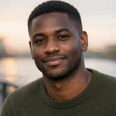 Young Black British man, short textured hair, warm expression, olive knit sweater